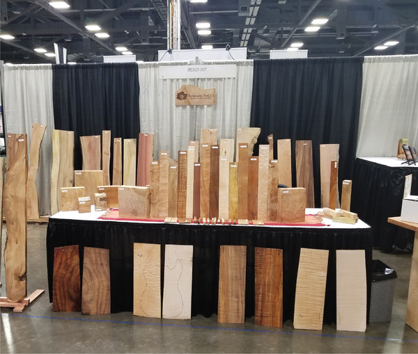 Many varieties of figured wood on floor and table display at a wood show